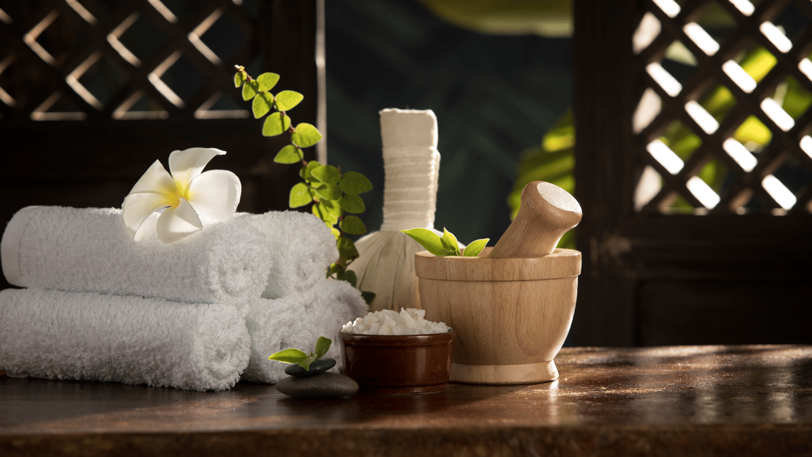  A serene spa setting with rolled white towels, a white flower, a mortar and pestle, and a bowl of salt at Rhythm Kumarakom