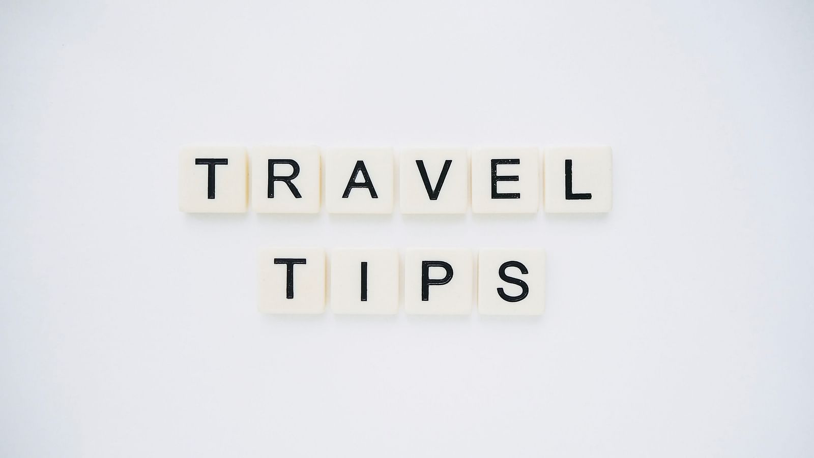 Travel tips written in scrabble tiles and placed on a table with white background