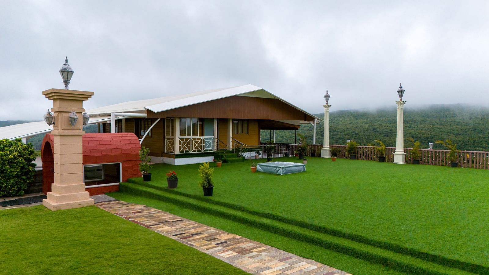 Shot of the facade of the resort clicked from the lush green lawn during a cloudy day | The Grand Legacy Resort and Spa