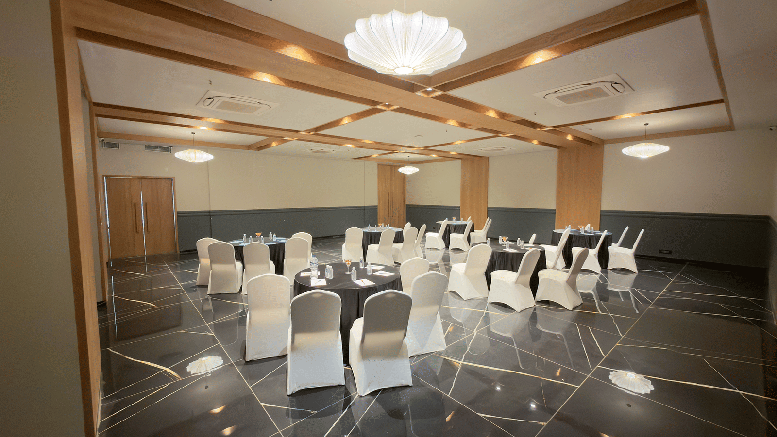 Vinti Resort event space set up with white chairs and tables, featuring a decorative ceiling and chandelier.