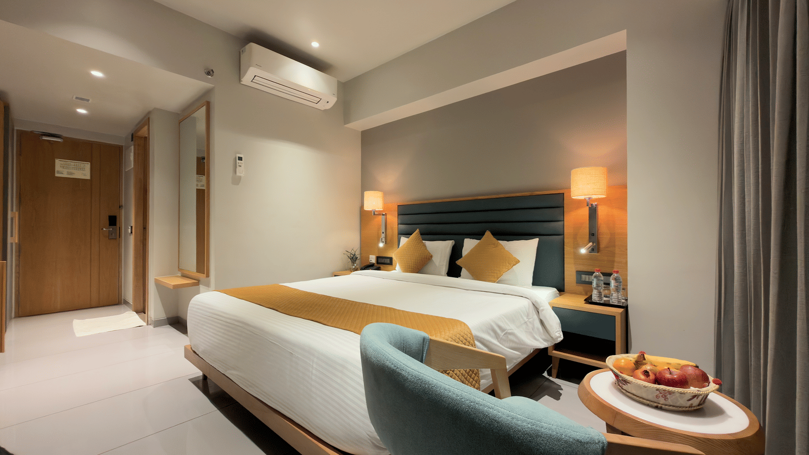 Hotel deluxe room with king size bed side tables, wall art, television, chair, desk, curtains, and window showing outdoor view