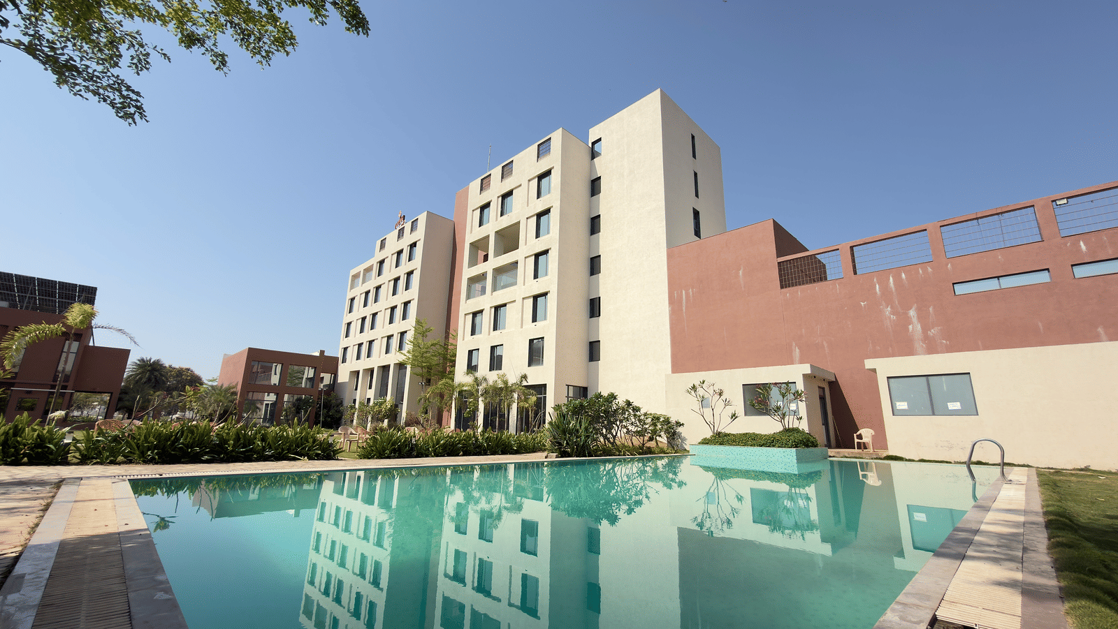 Vinti Resort building with a swimming pool and trees in the foreground.