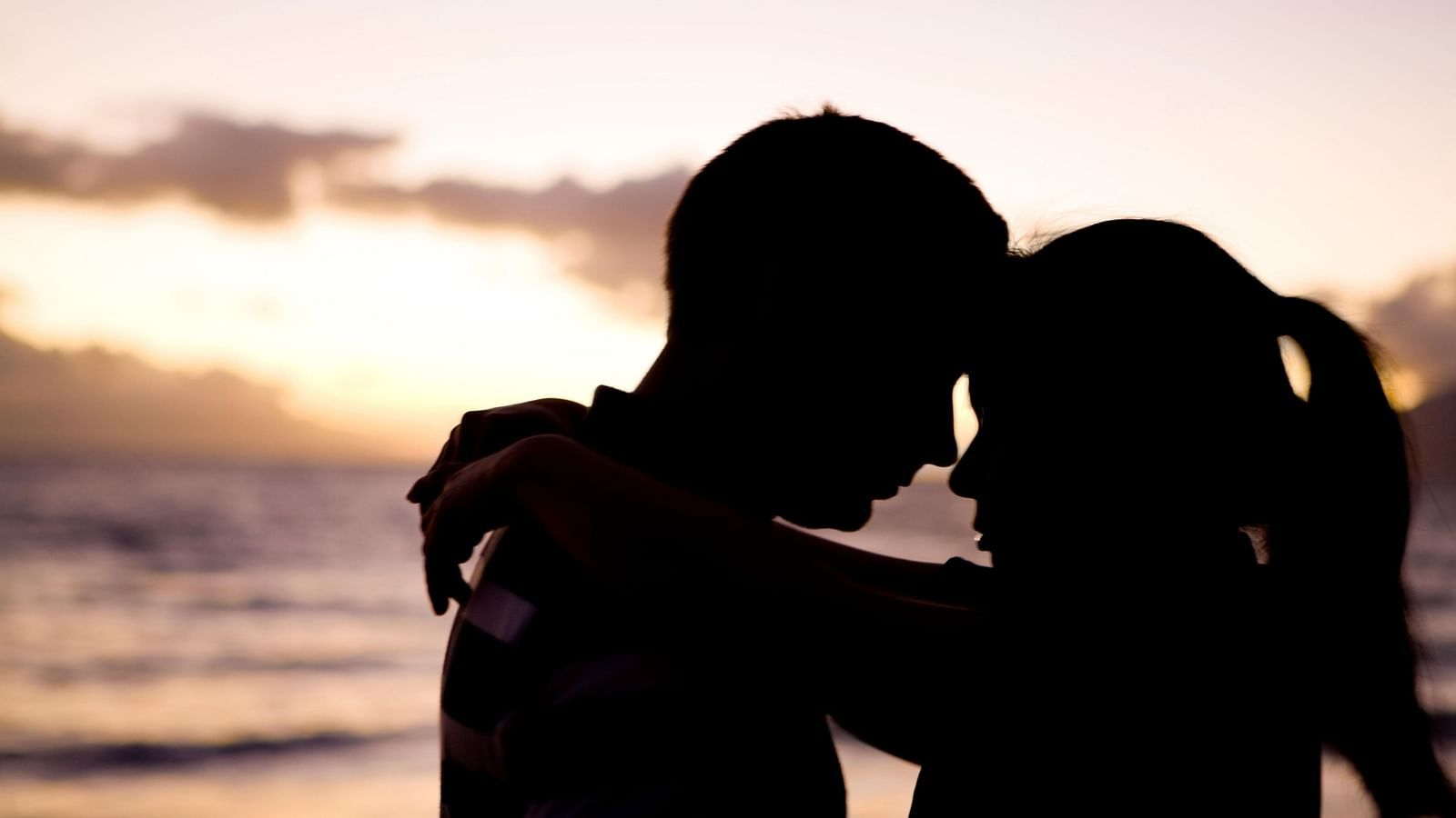 a couple holding each other in front of a beach - Rhythm Kumarakom