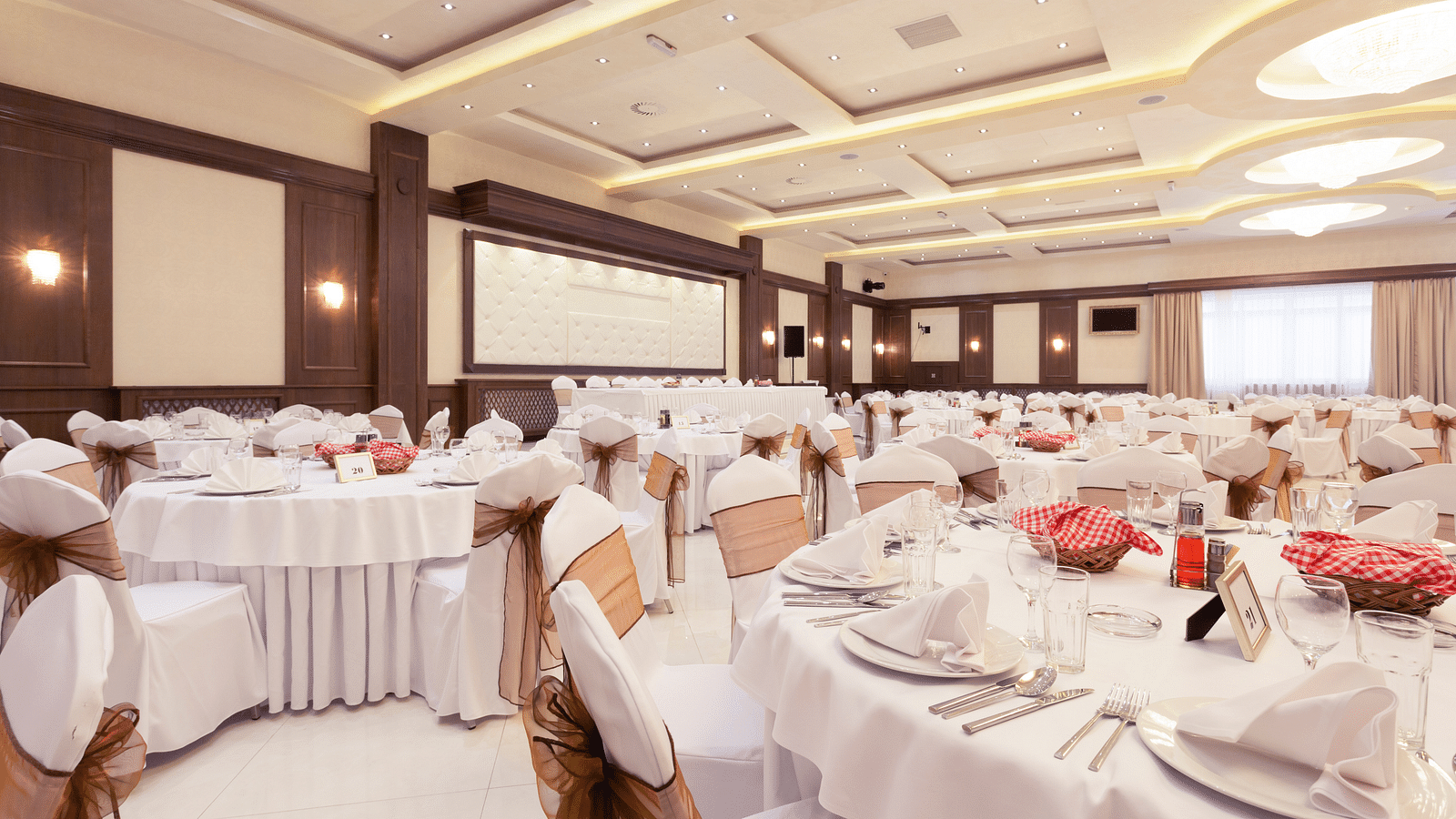 an image of a banquet hall with white decor and white linen-covered tables and ambient lighting - at Rhythm Kumarakom
