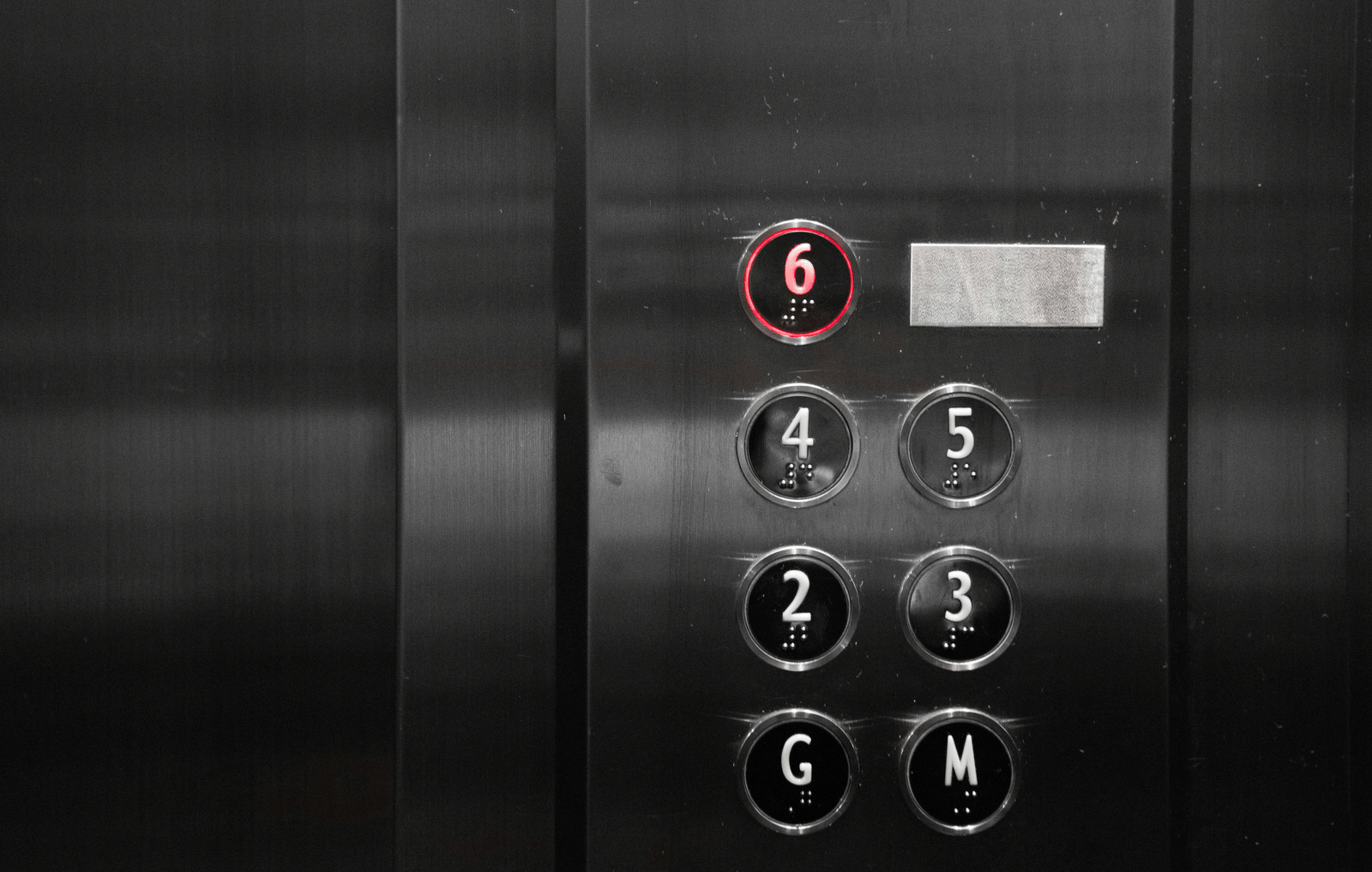 A close-up of the metal control panel inside a lift showing numbered floor buttons.