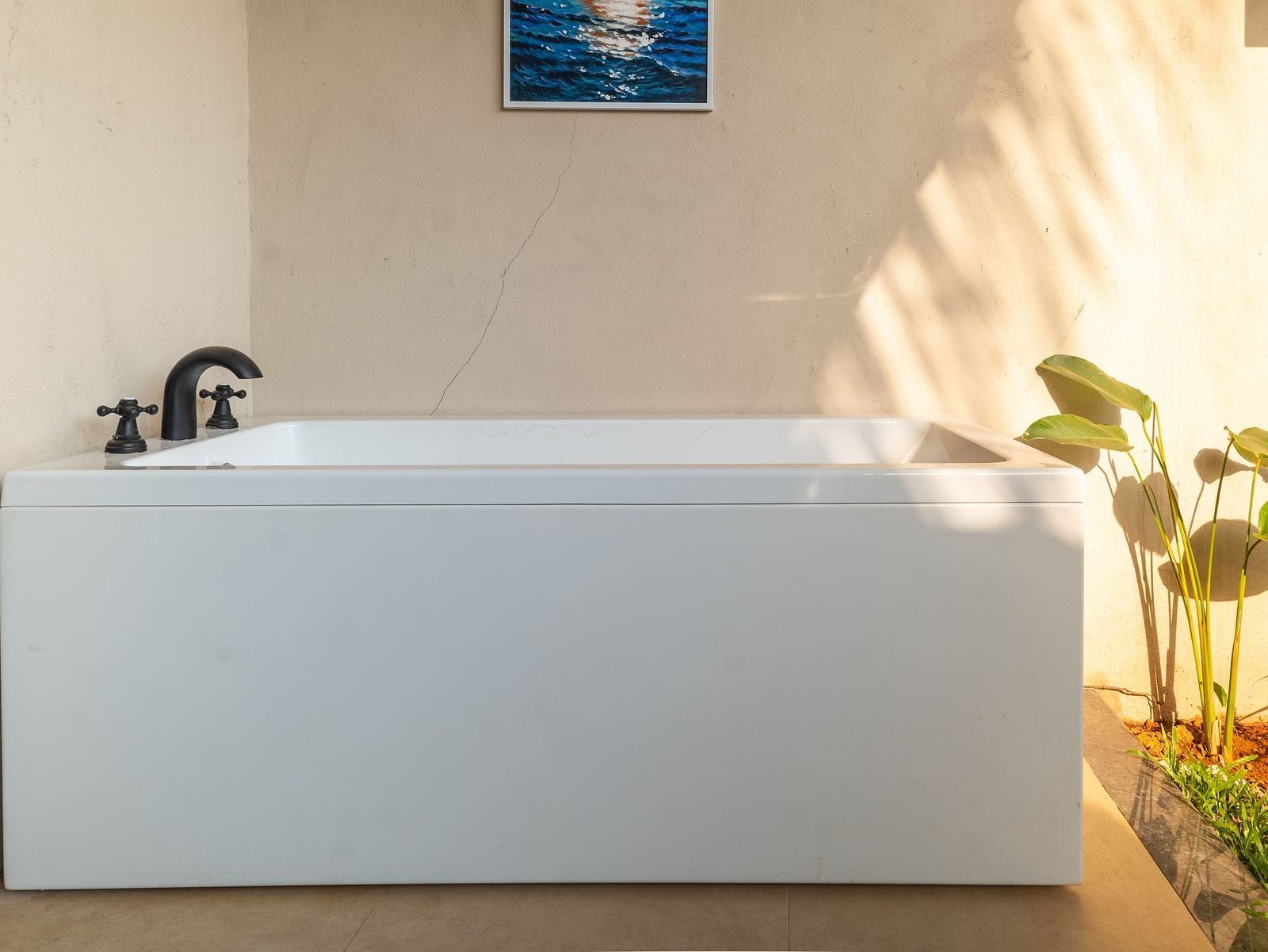 Outdoor bathtub setup surrounded by potted plants and natural sunlight at Kssemya.