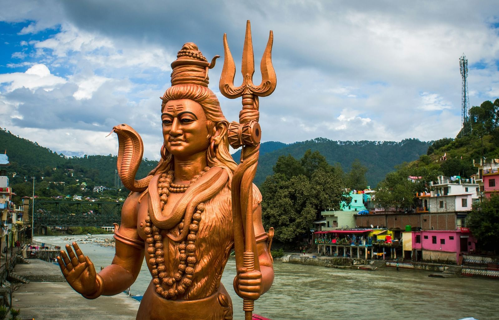 Golden statue of Shiva on the banks of a river.