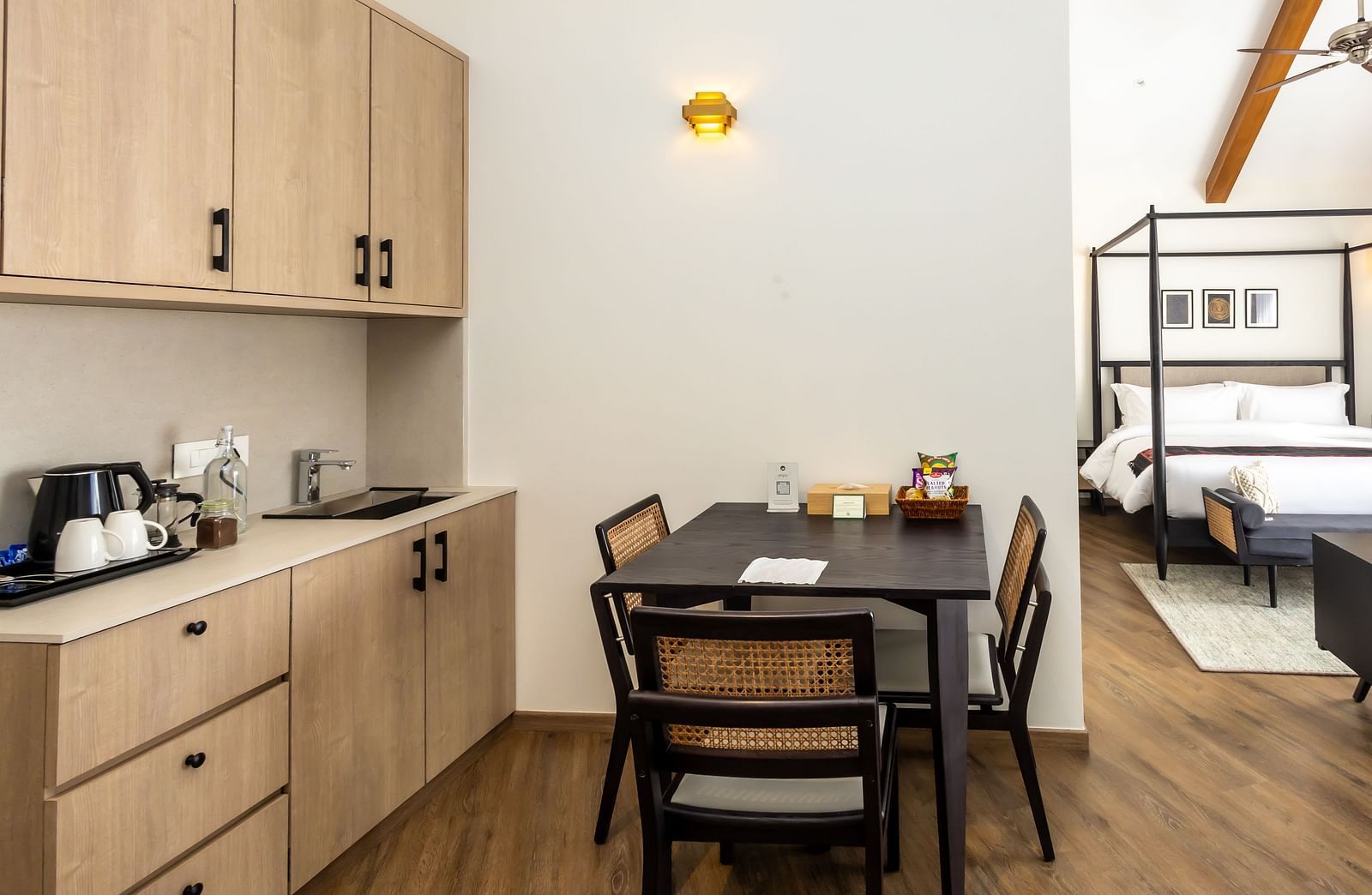 Wooden cupboards with kitchen essentials and a dining table with chairs arranged around it at Nivasana Manali.