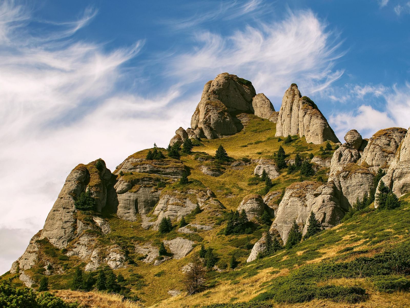 A rocky mountain peak under a blue sky with white clouds.