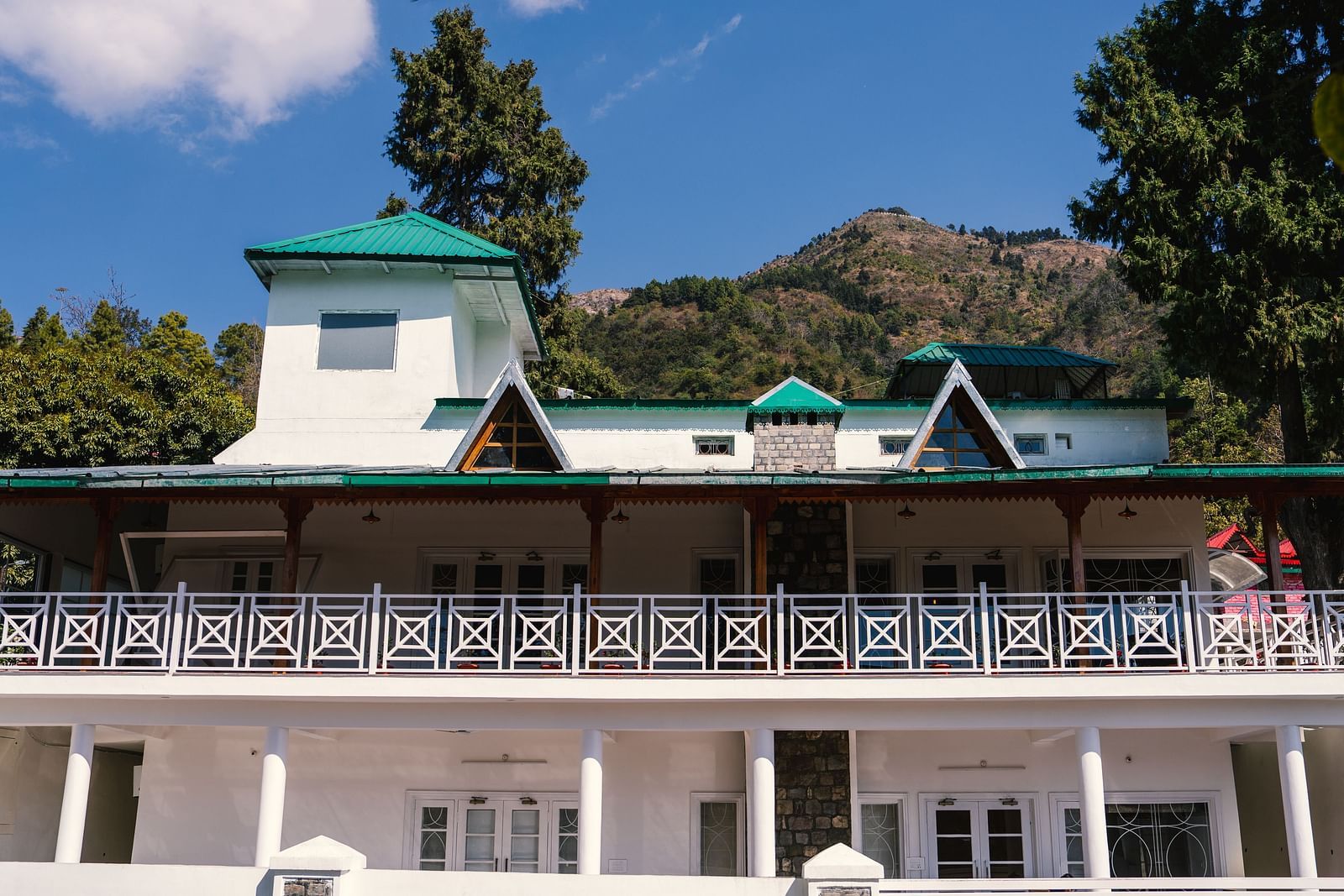 Facade of BluSalzz Villas - The Green Roof, Bhimtal, is set against a stunning backdrop of mountains and lush trees.