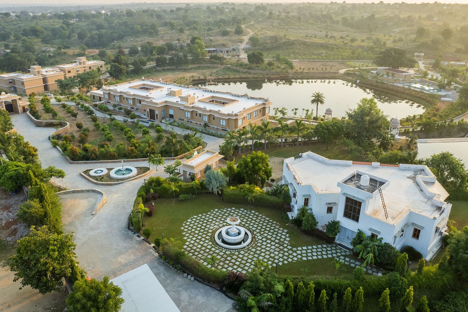 An aerial shot of our property surrounded by greenery and two water bodies - Rajbagh Wellness, Udaipur