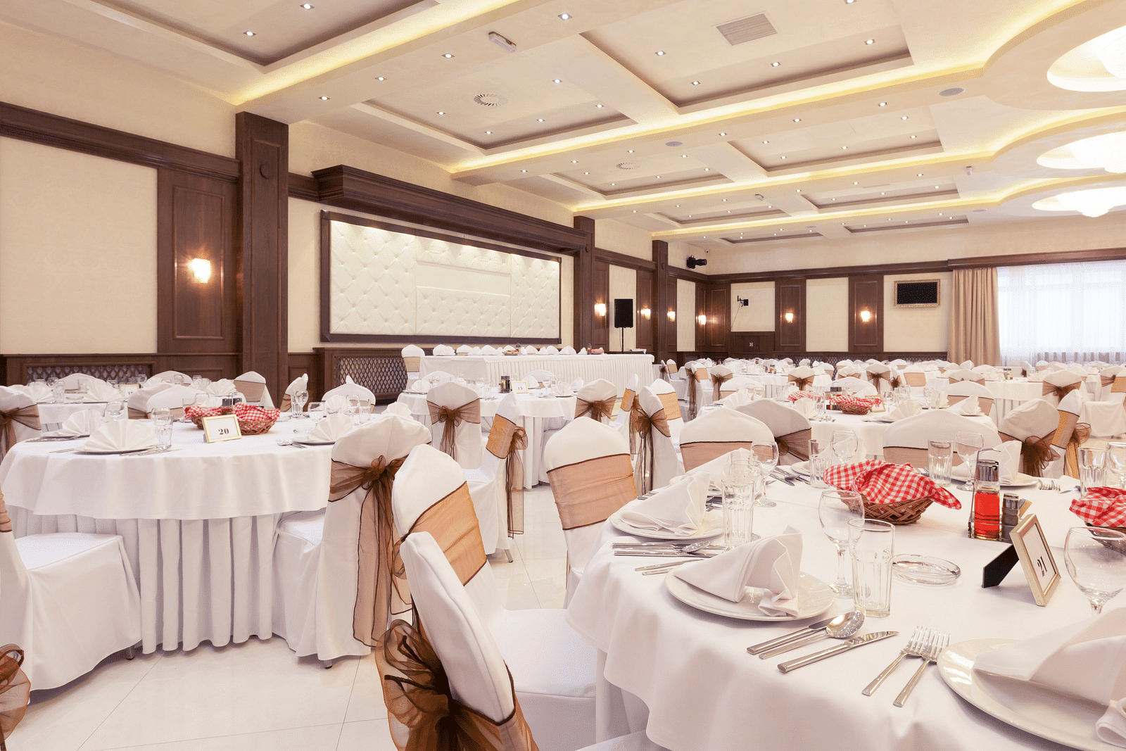an image of a banquet hall with white decor and white linen-covered tables and ambient lighting - at Rhythm Kumarakom