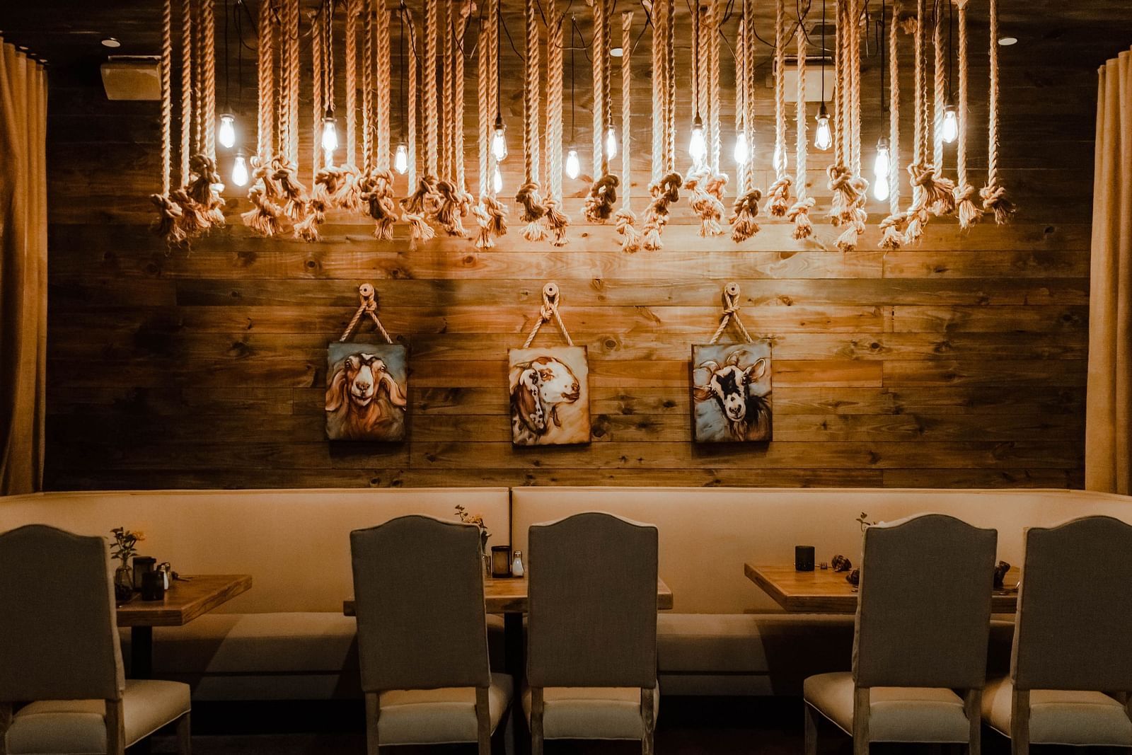 A dining area with a long table, modern chairs, hanging light fixtures, and decorative wall-mounted artwork.- The Grand Hotel & Ballroom, McKinney