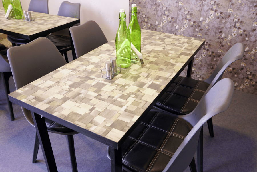 Restaurant tables with grey chairs and green glass water bottles in a casual dining area