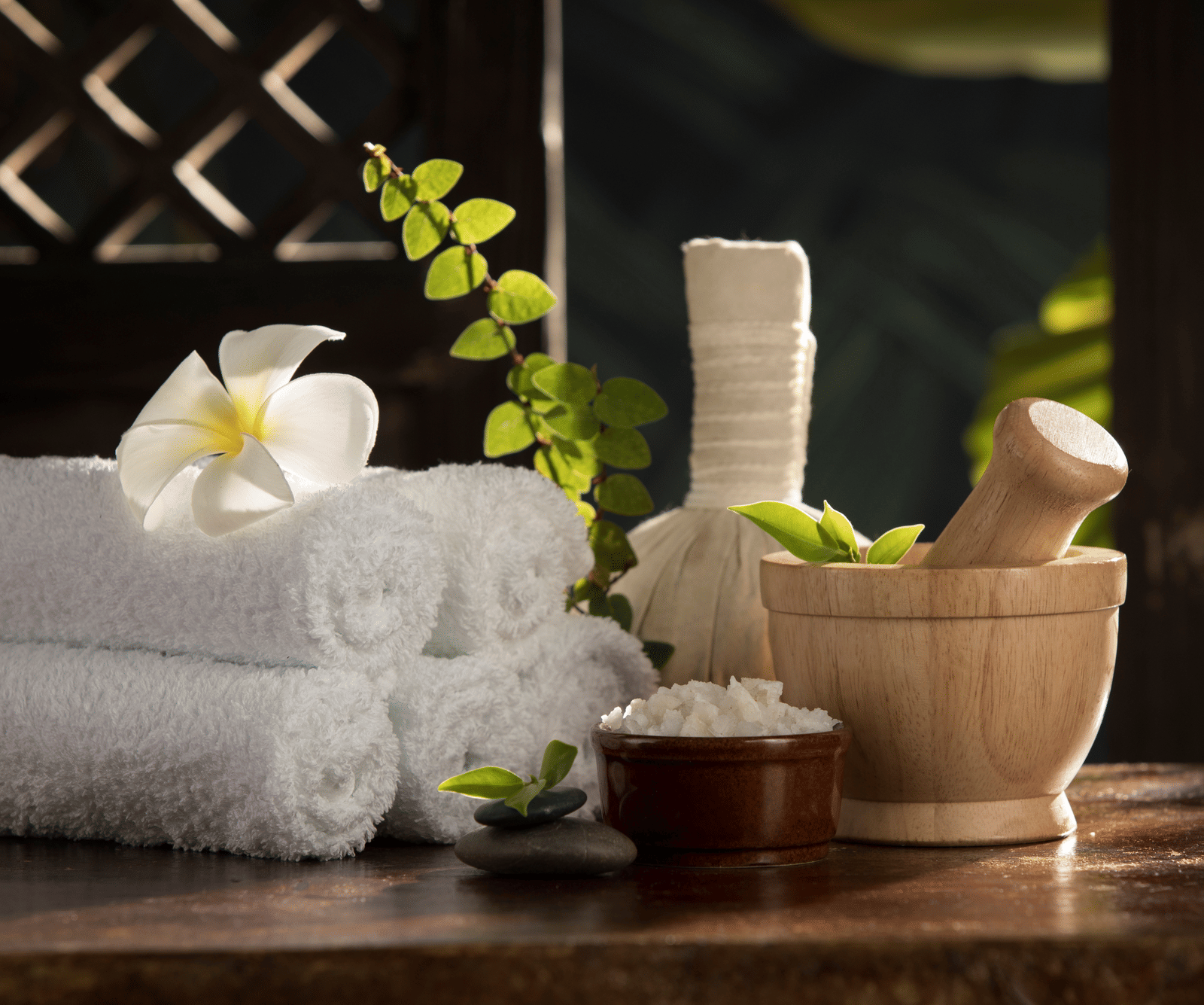  A serene spa setting with rolled white towels, a white flower, a mortar and pestle, and a bowl of salt at Rhythm Kumarakom