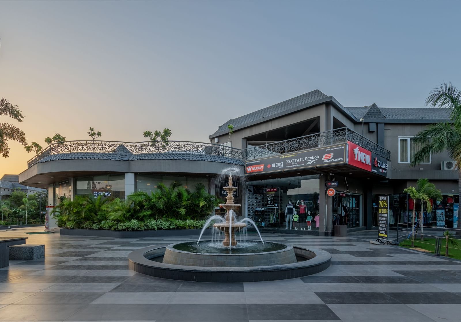 A wide exterior shot of Hotel Highway King Shahpura, featuring a fountain and pathways.