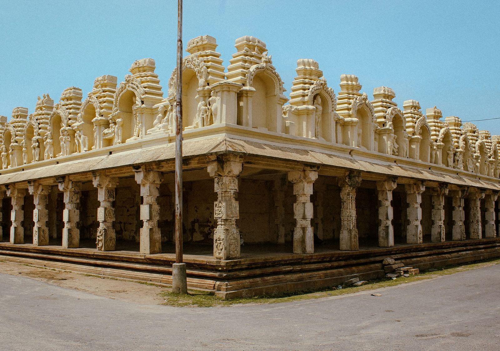 Exterior photograph of a temple with multiple pillars and a blue sky.