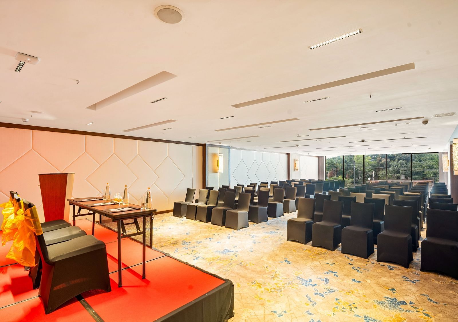 An image of a Godavari conference hall with black chairs facing the podium at Grand Vijayawada by GRT Hotels.