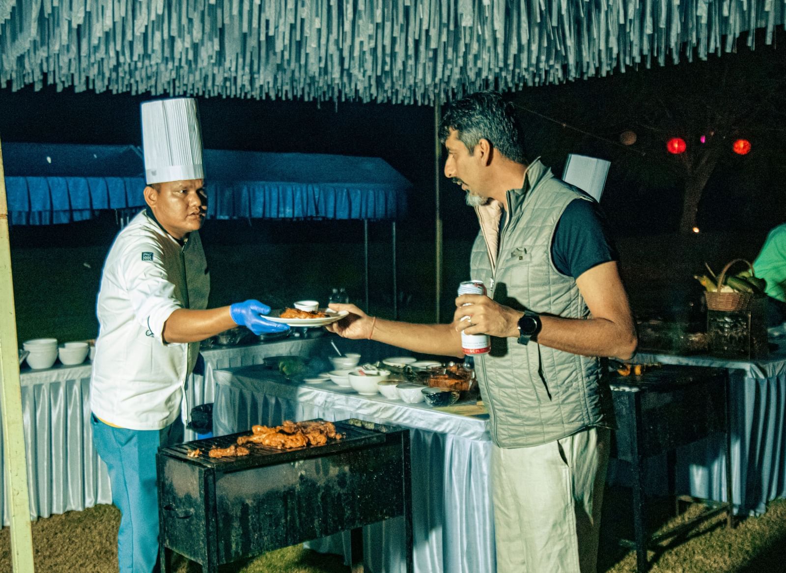Chef serving food to a guest from a buffet counter under a canopy at Fireflies Resorts, Kabini.