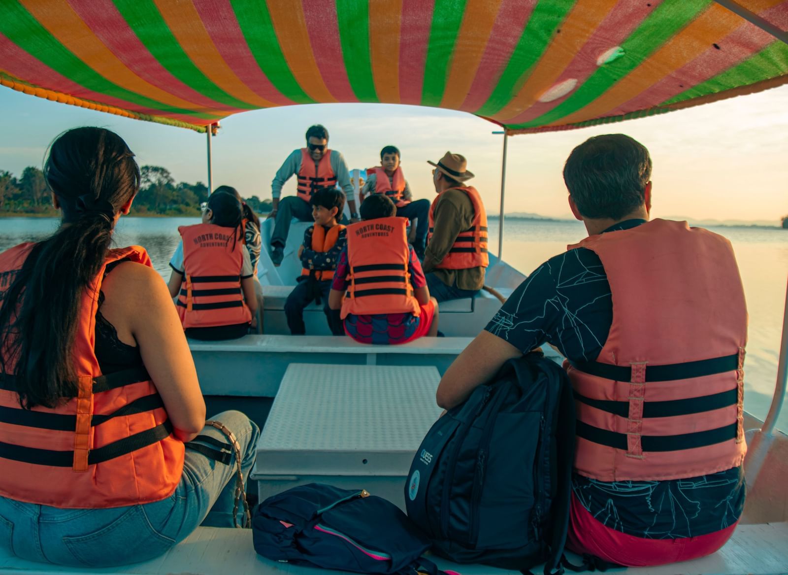 Guests wearing life jackets seated on a covered boat during a water safari at Fireflies Resorts, Kabini.