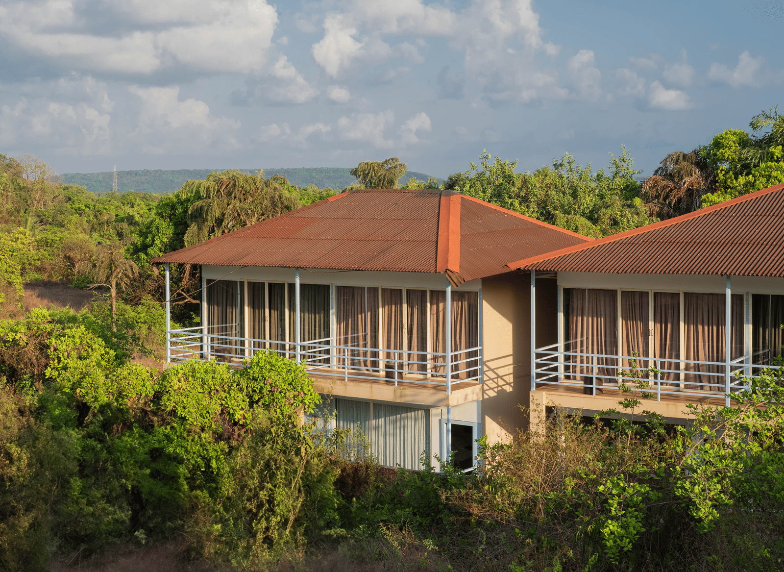 An aerial view of our accommodation buildings with orange-tiled balconies, surrounded by lush greenery - Perfectstayz Koko Maya