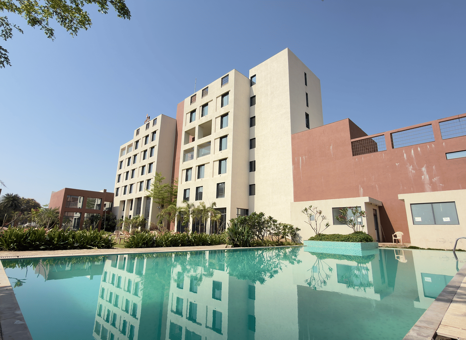 Vinti Resort building with a swimming pool and trees in the foreground.