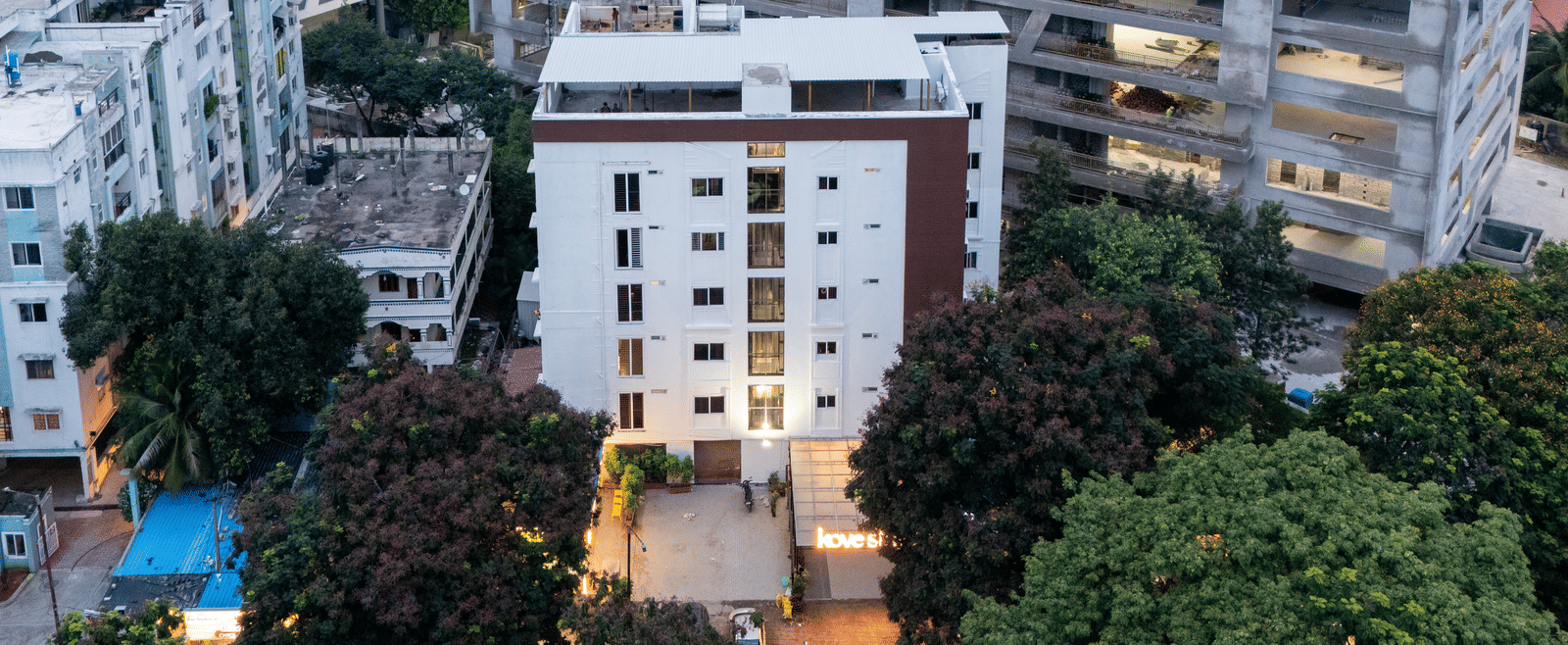 Aerial view of Kove Smart Stays, Hyderabad, seen at a partially dark hour, with the lights of the entryway turned on.