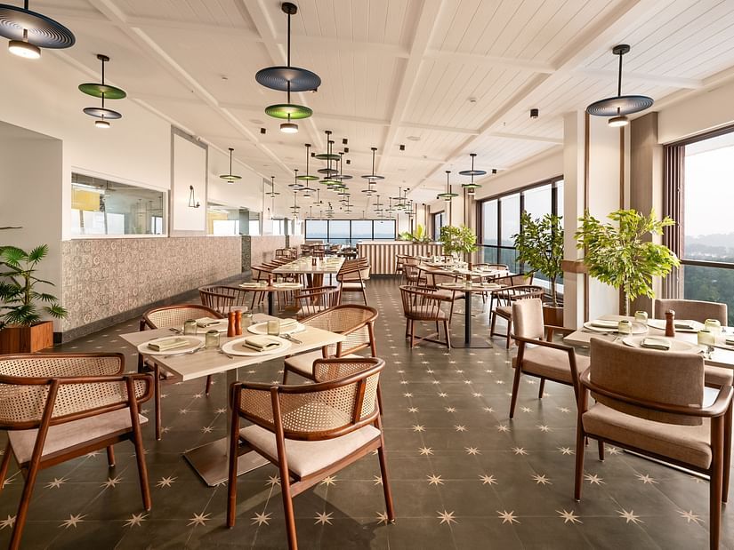 Elegant dining space with tables and chairs, featuring fancy lights hanging from the ceiling at Cloud9 Sarovar Premiere, Palolem Goa.