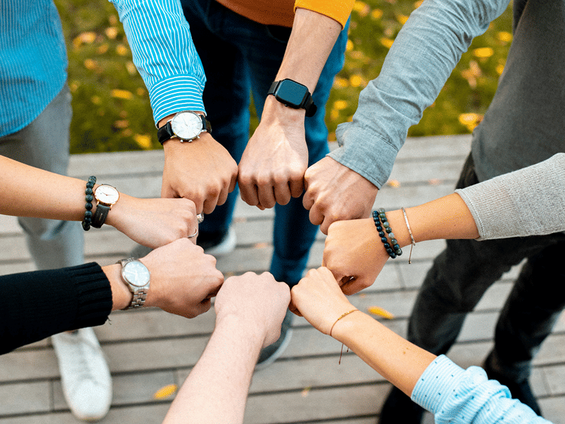 A group of 7 people doing fist bump, emphasising team building in Goa