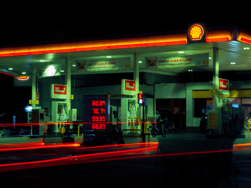 An eye-level shot at night of a gas station with a bright red neon light framing the roof of the gas station.