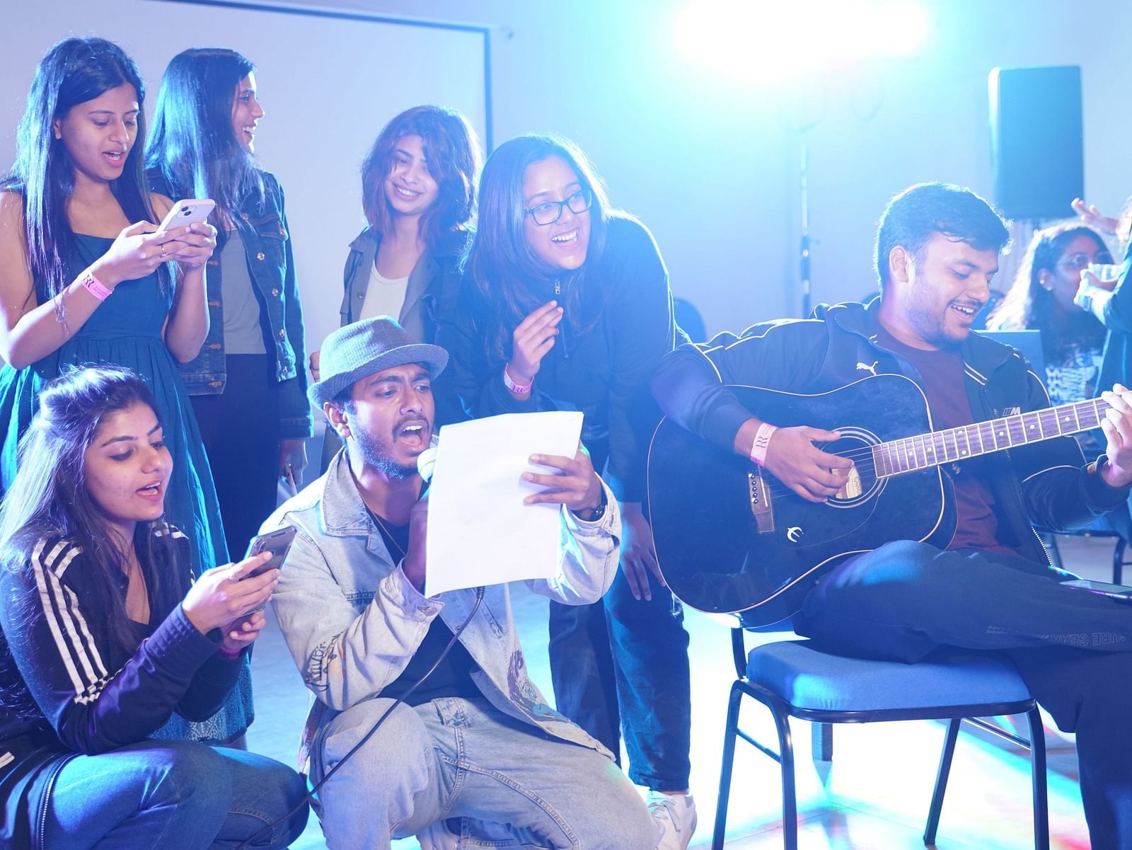 A group of people at Ravishing Retreat singing and jamming while another person is sitting on the chair and playing guitar