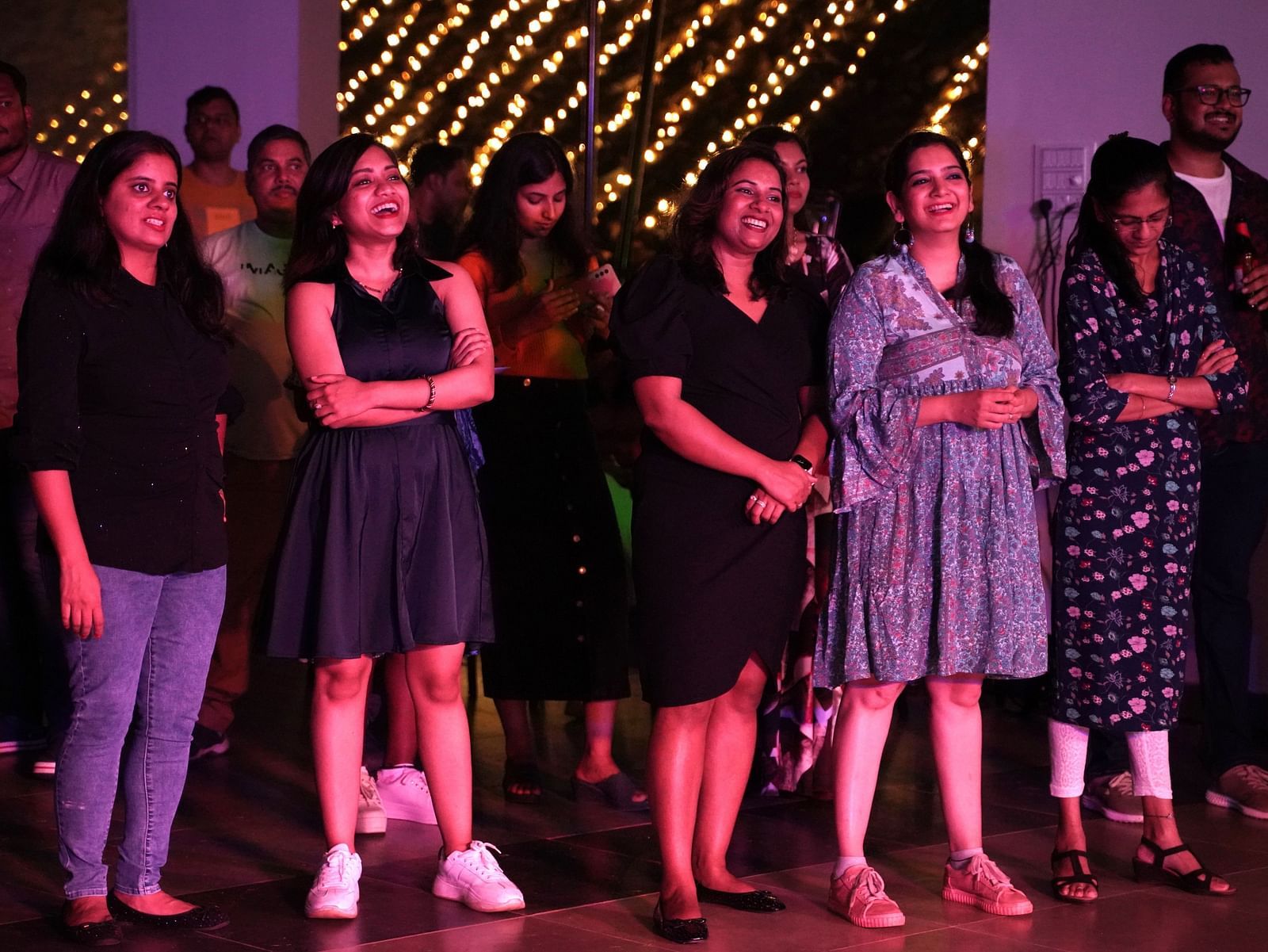 A group of ladies standing and smiling under vibrant lighting at Ravishing Retreat 
