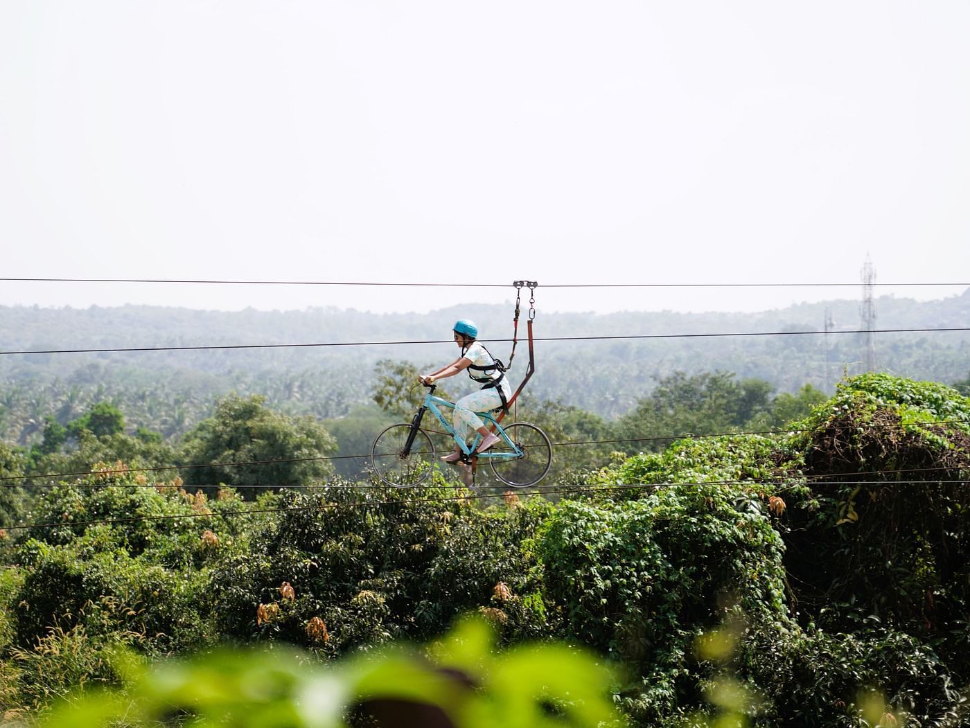 Image of a person in the air enjoying zip-cycling at Ravishing Retreat on a sunny day amid greenery