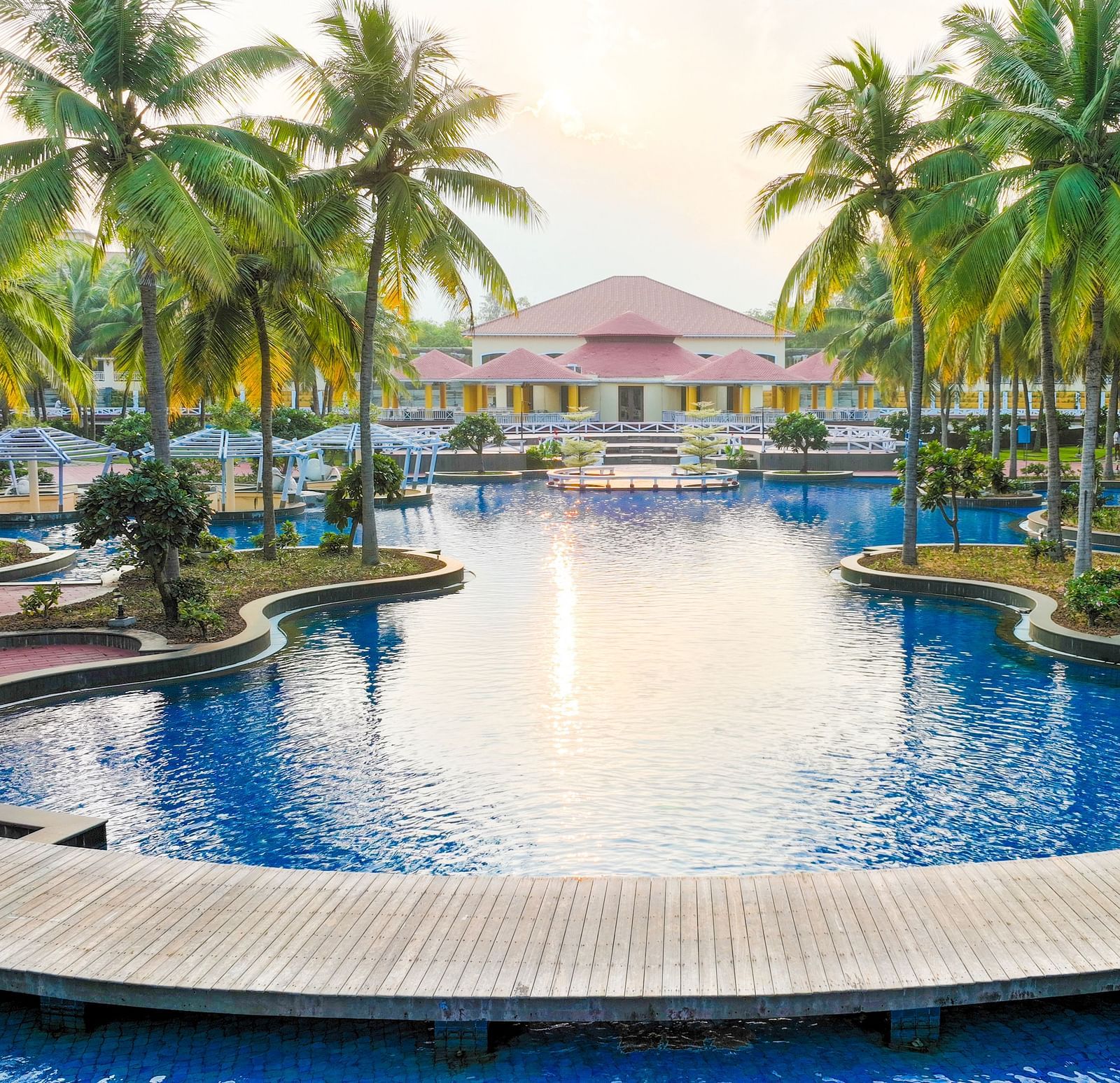 Swimming Pool with a view of cocunut trees on the side at Ocean Spray Puducherry