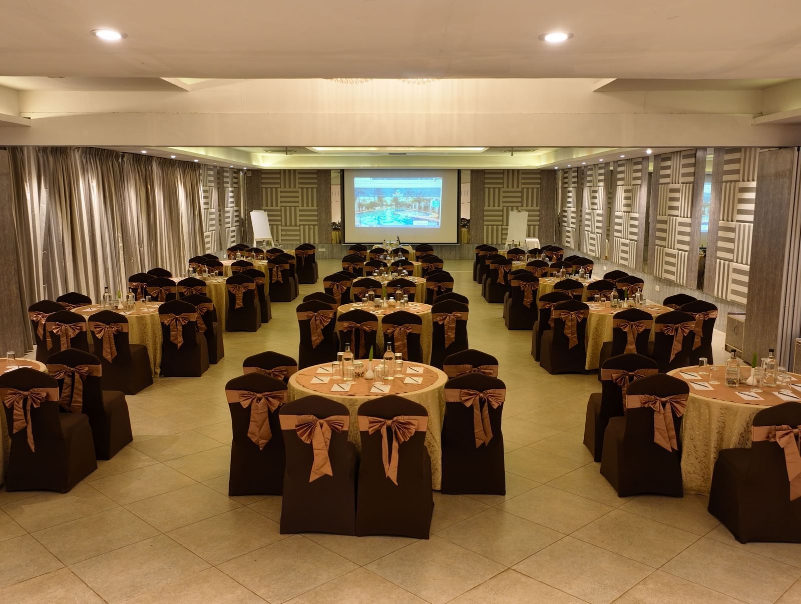 Banquet hall with brown chair covers arranged around round tables at Grande Bay Resort & Spa.