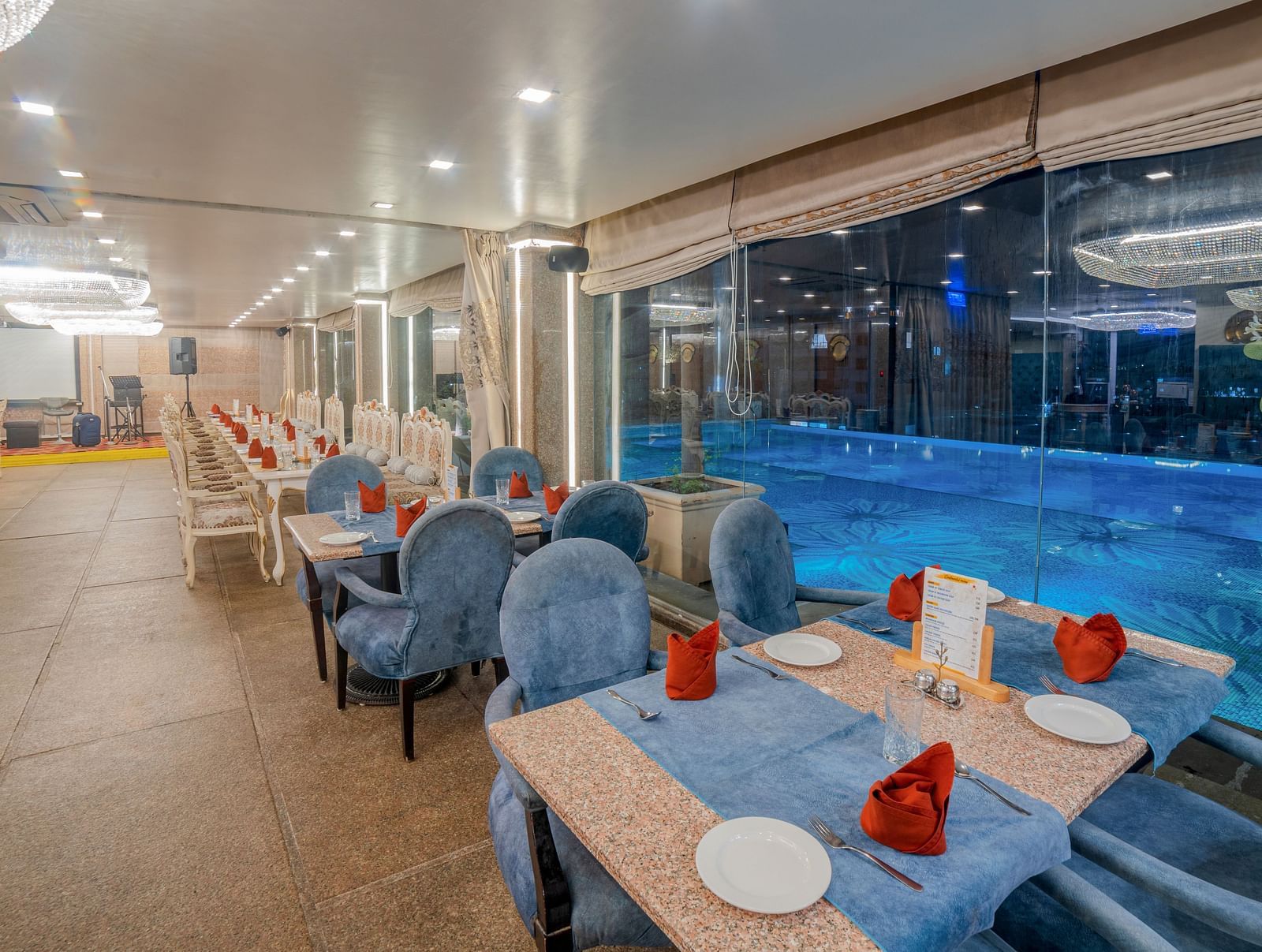An indoor dining setup next to a pool at Hotel Ashok Nagpur. 