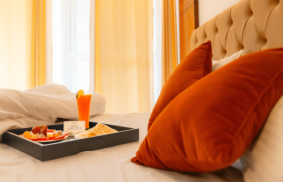 A breakfast platter placed on a bed at  Montclair Ananta, Elite.