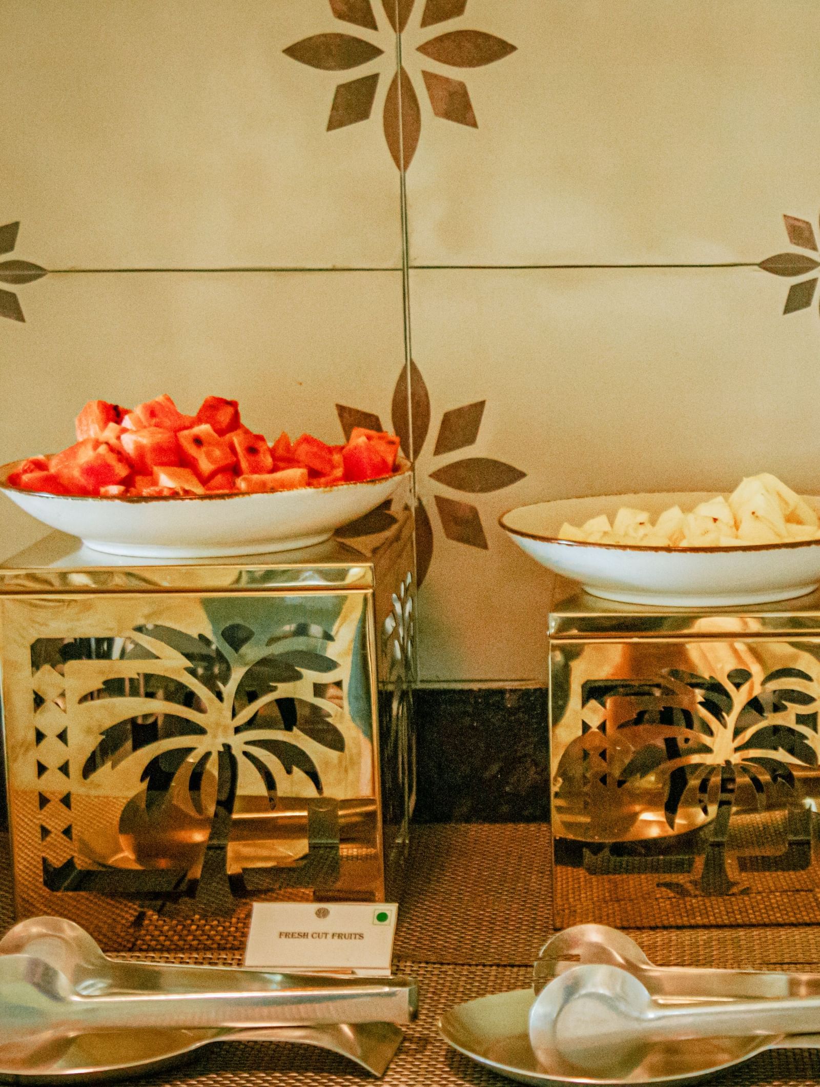 Breakfast counter with cereal dispensers, fruit bowls, and cutlery placed neatly on a tiled wall backdrop at Fireflies Resorts, Kabini.