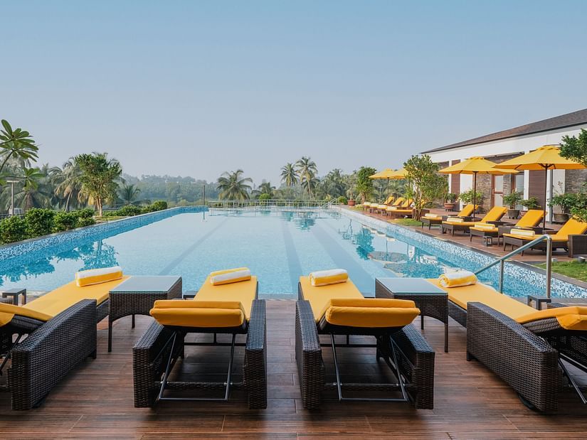 an image of crystal clear swimming pool surrounded by sun loungers at Cloud9 Sarovar Premiere, Palolem, Goa.