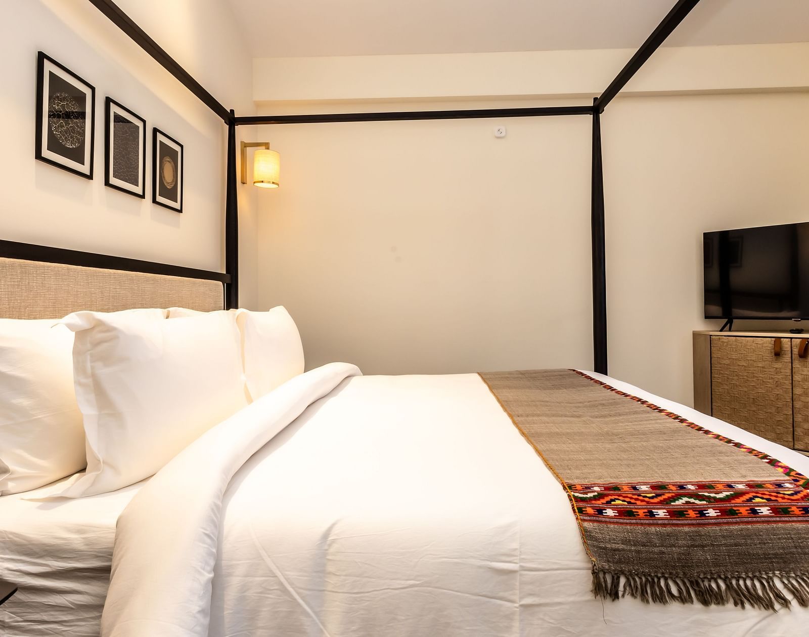 Bedroom with a four-poster bed and patterned throw at Nivasana Manali.