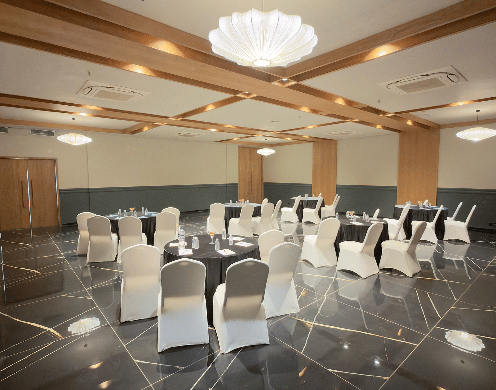 Vinti Resort event space set up with white chairs and tables, featuring a decorative ceiling and chandelier.