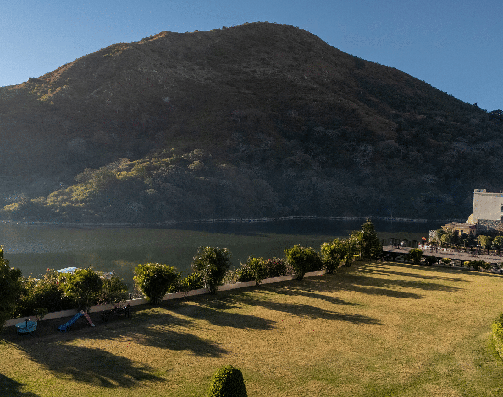 Mountain with a winding road, trees, and water visible, sunny day - Via Lakhela Resort & Spa