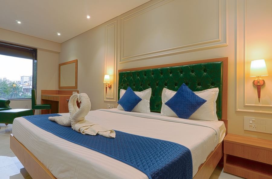 A double bed with a green high chair next to it inside deluxe suites - Magnus Nexstar Suites, Pune