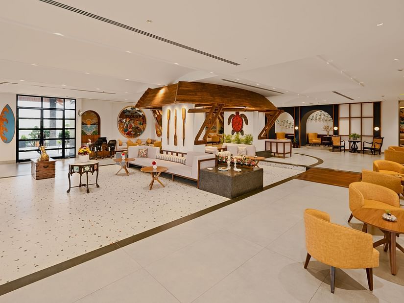 Lobby space with sofas and chairs, featuring wall hanging turtle craft, paddles, and candle holders at Cloud9 Sarovar Premiere, Palolem Goa