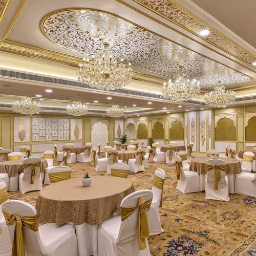 Lavish ballroom with ornate ceiling, multiple chandeliers, and round tables with white and gold accents - Heritage Village Resorts & Spa.