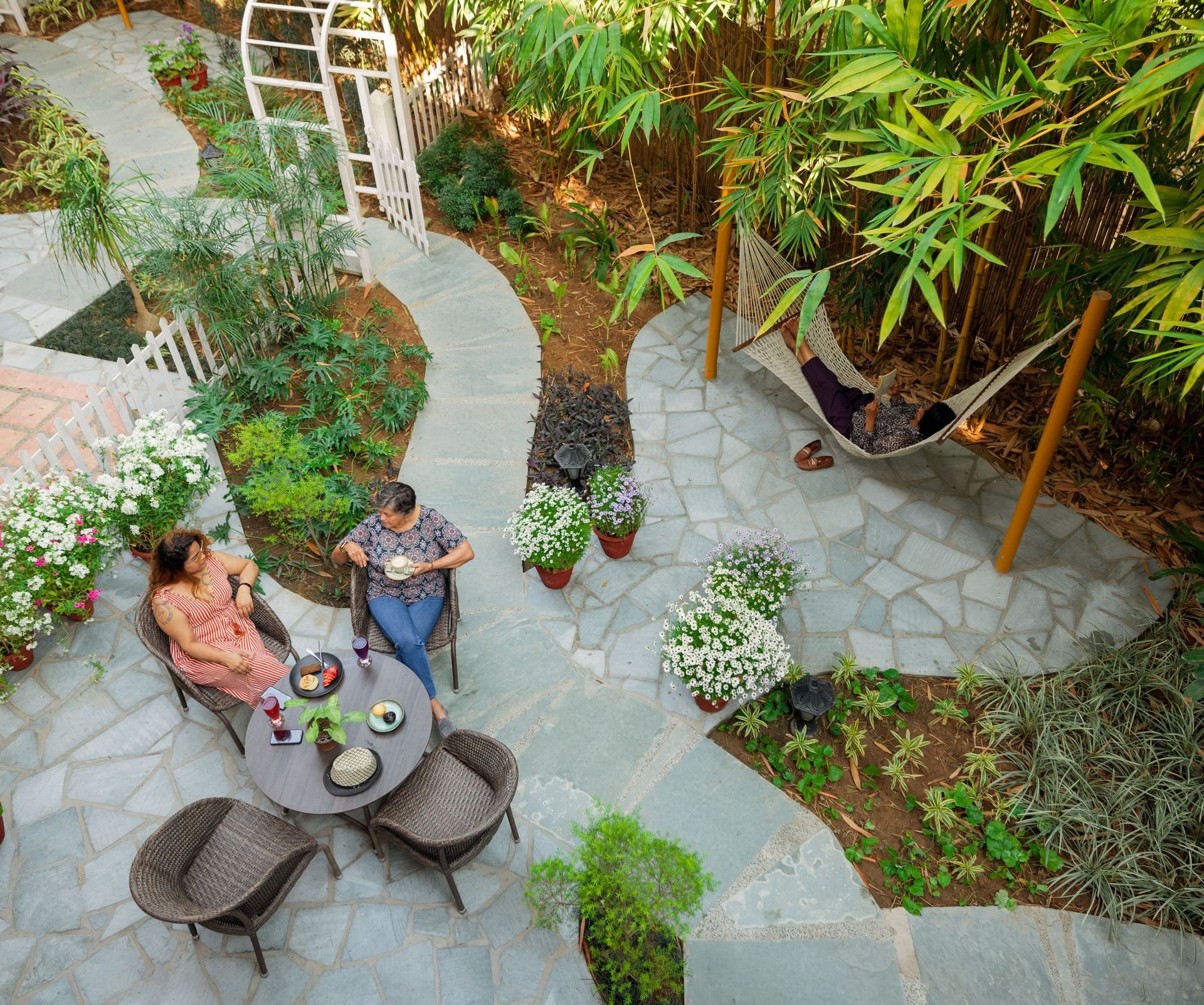 Guests relaxing at a garden table surrounded by tropical plants at Karma Chalets.