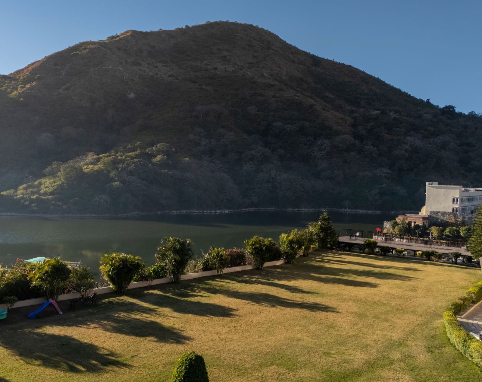 Mountain with a winding road, trees, and water visible, sunny day - Via Lakhela Resort & Spa