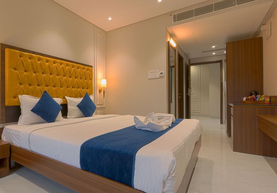 A double bed with cushioned headboard and side tables inside the deluxe suite - Magnus Nexstar Suites, Pune