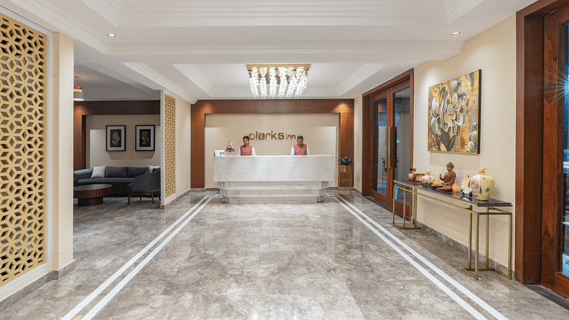 Reception at Clarks Inn, Dehradun featuring glossy floor leading to the reception desk where two receptionists are present