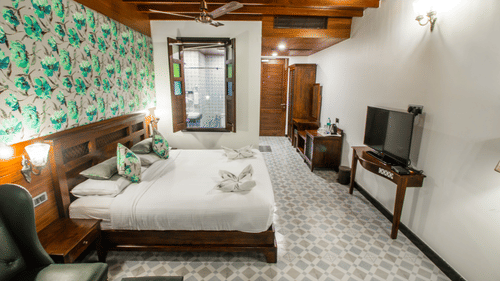 a double bed with a tv opposite it and a lamps on either side of the bed inside Casa Earth - Symphony Summer Sand Beach Resort And Spa, Neil Island